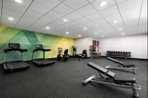 Gym with treadmills, exercise bikes, weights, and colorful accent wall