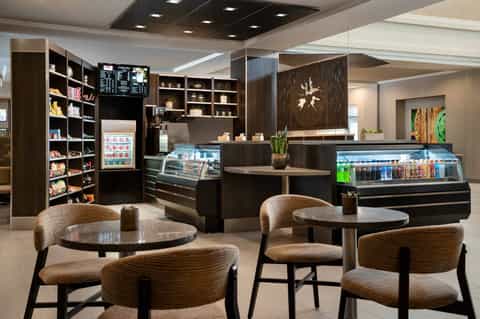 Modern café interior with dark wood cabinetry, display cases, seating area, and contemporary furnishings