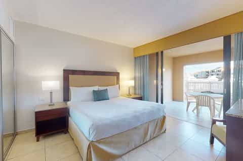 Modern hotel bedroom with queen bed, balcony access, and contemporary furnishings