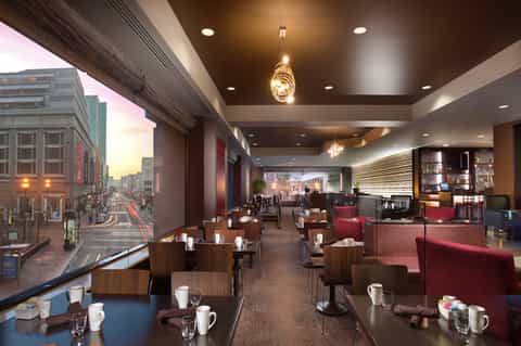 Upscale hotel lounge with city views, modern lighting, and burgundy accent seating