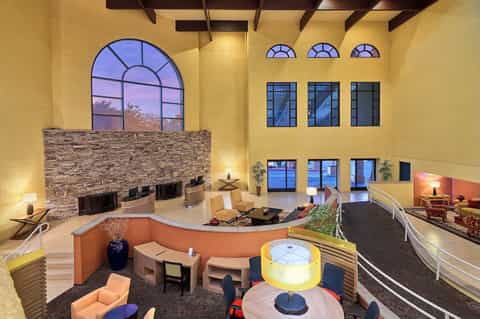 Grand multi-level atrium lobby with dramatic yellow walls, stone fireplace, and contemporary seating areas