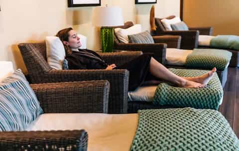 Relaxation lounge with woman in wicker chair and green patterned ottoman seating