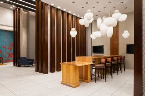 Modern hotel lobby with wood accent walls, elegant pendant lights, seating area, and contemporary design