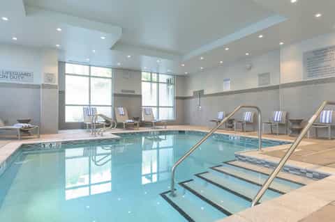 Indoor aquatic center with lap pool, loungers, and large windows for natural light