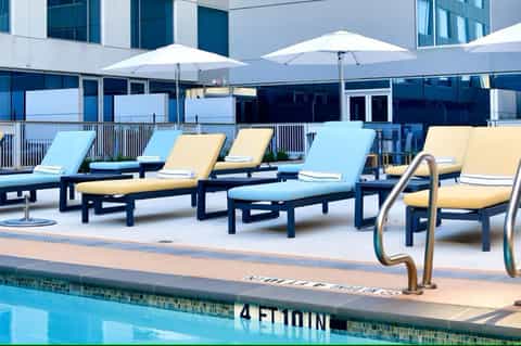 Modern rooftop pool deck with lounge chairs in blue and yellow cushions under white umbrellas