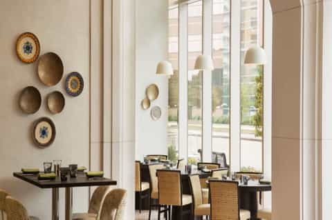 Hotel dining room with floor-to-ceiling windows, pendant lighting, and wall plate decor