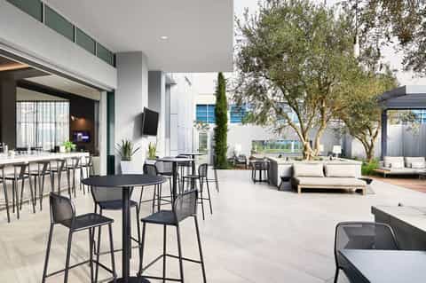 Modern resort courtyard with outdoor bar, seating areas, and Mediterranean landscaping