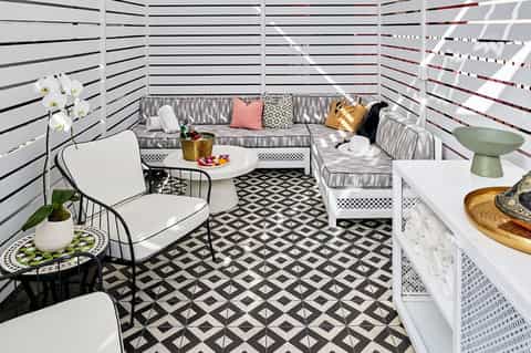 Modern rooftop lounge with white privacy screens, gray seating, geometric black and white floor tiles