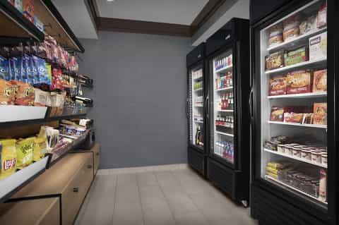 Hotel convenience store interior with refrigerated cases, snack shelves, and organized product displays