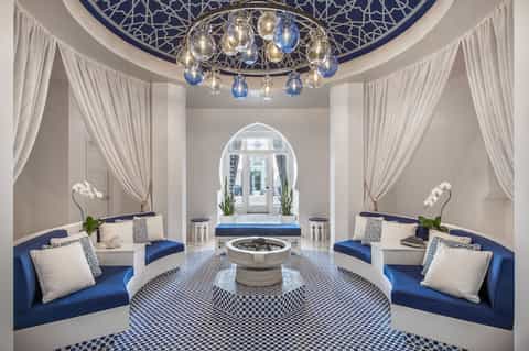 Luxurious spa sanctuary with blue and white decor, ornate chandelier, marble fountain, and archway