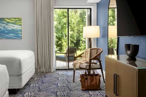 Luxury suite with curved white sofa, blue accent wall, forest views through glass doors