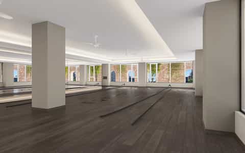 Spacious fitness center with mirrored walls, wooden flooring, and bright windows