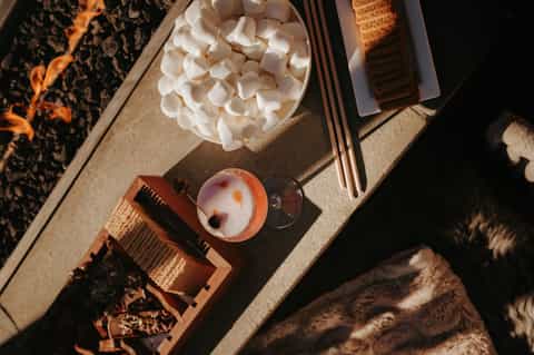 Overhead view of spa amenities including marshmallows, cocktail, and relaxation items on textured surface