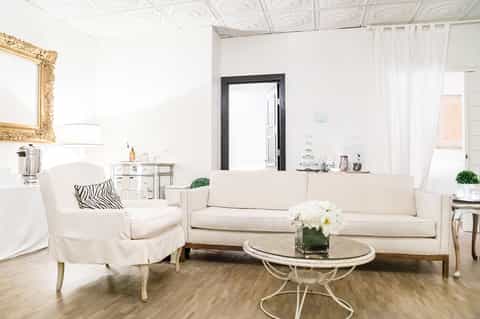 Bright spa treatment room with white furniture, cream sofa, and elegant décor