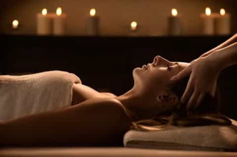 Woman receiving relaxing massage with candlelit ambiance and soft background lighting