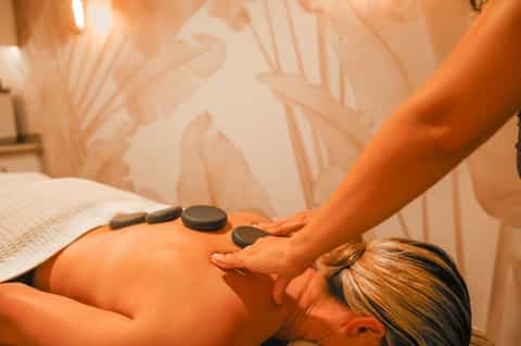 Therapist performing hot stone massage on client's back