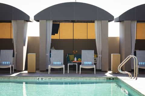 Three dark dome-shaped cabanas with white loungers positioned poolside, featuring modern architectural design