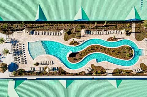 Aerial view of snake-shaped resort pool with turquoise water and beige loungers