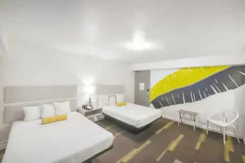 Modern hotel bedroom with two white beds and artistic yellow and gray wing wall mural