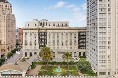 Historic beaux-arts hotel building with ornate facade, palm trees, and urban plaza setting