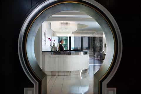 Hotel reception desk viewed through modern circular archway with staff member at counter