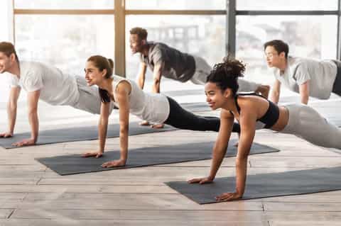 Group fitness class performing plank exercises on yoga mats with city skyline views