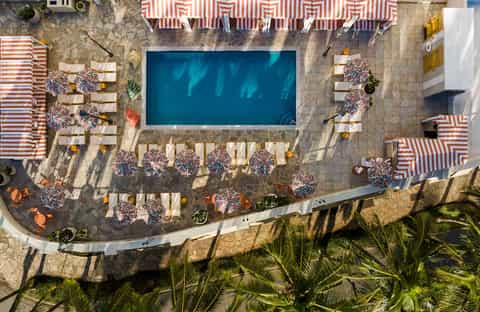 Overhead view of resort pool surrounded by striped loungers and tropical landscaping