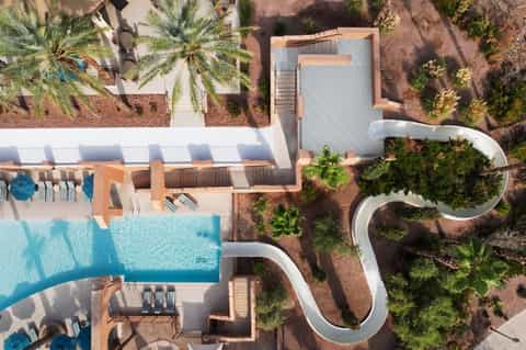 Aerial view of resort with curved pathways, pool, and palm trees in desert landscape