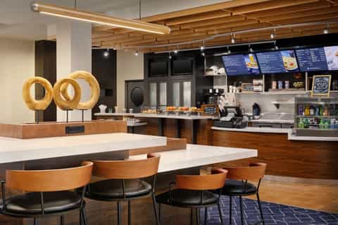 Contemporary café interior with wooden ceiling, counter seating, menu boards, and decorative donut signage