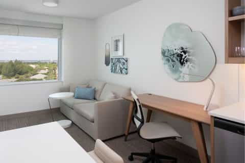 Modern hotel room interior with window view, neutral furnishings, and work desk