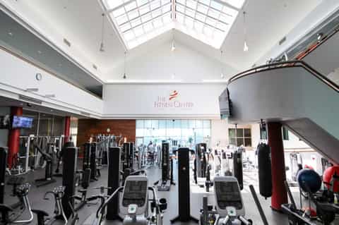 Spacious indoor fitness center with high ceilings, skylights, exercise bikes, and red support columns