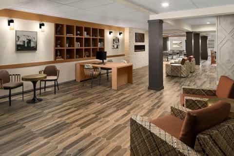 Contemporary hotel lobby with wooden shelving, reception desk, and wood-grain flooring
