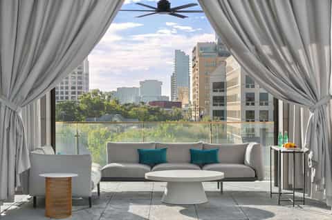 Modern terrace lounge with gray sofa, sheer curtains, and expansive city skyline views