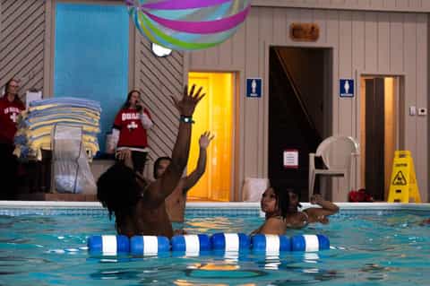 Children's swimming lesson in indoor pool with instructors and colorful decorations