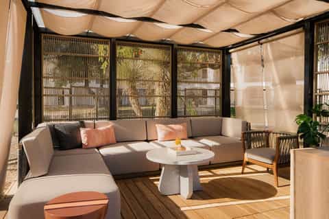 Modern poolside lounge area with curved sofa, shade sail, and geometric screens