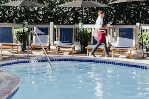 Resort pool with metal railings, lounge chairs, umbrellas, and person jogging past