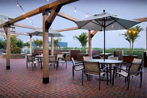 Outdoor pergola dining area with umbrellas and coastal marsh views
