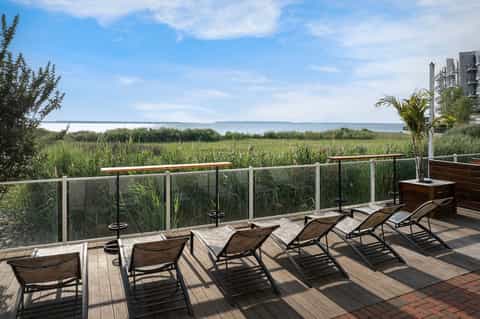 Waterfront deck with lounge chairs overlooking marshland and bay water