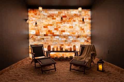 Spa relaxation room with salt wall, two lounge chairs, and candlelit ambiance