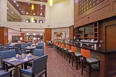 Contemporary restaurant and bar with blue patterned chairs, dark wood accents, and open kitchen counter