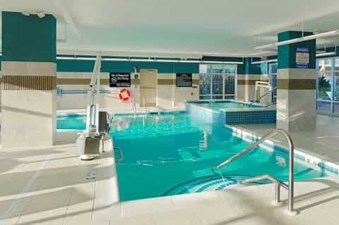 Indoor swimming pool facility with turquoise water, teal and beige tiled walls, large windows