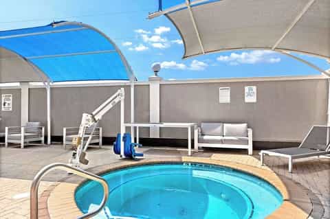 Outdoor hot tub with retractable shade sails and lounge seating on wooden deck