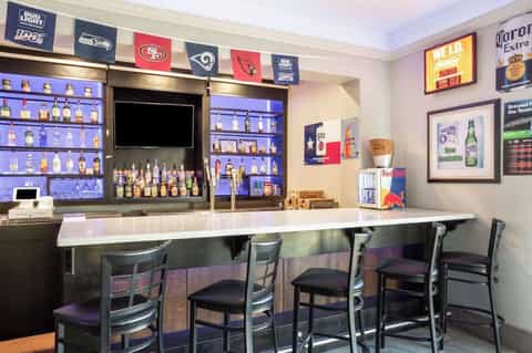 Sports bar with illuminated bottle display, sports memorabilia, and bar seating