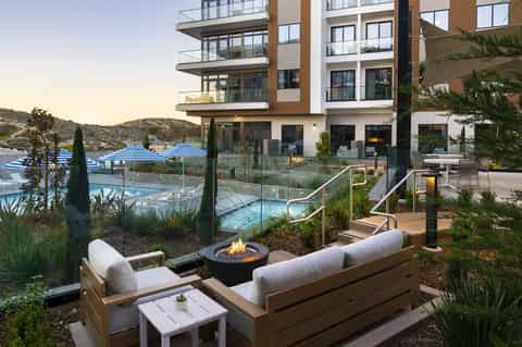 Residential fire pit lounge area overlooking tiered pools and hillside landscape at dusk