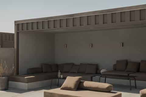 Modern outdoor seating area with dark sofas, beige pillows, and minimalist architectural design