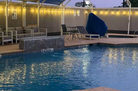 Indoor pool area with covered seating, loungers, and blue umbrellas