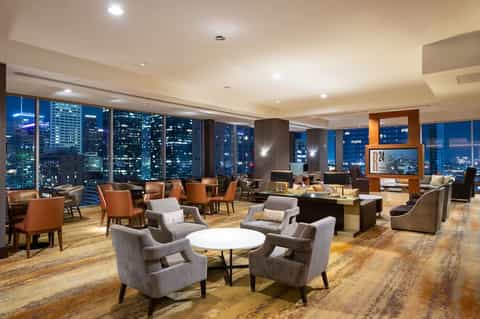Luxury lounge with floor-to-ceiling windows, city skyline views, and modern seating areas