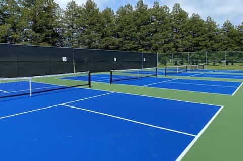 Professional outdoor tennis courts with blue and green playing surfaces, white nets, and black backboards