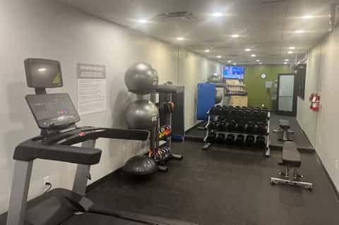 Modern fitness center with exercise bike, stability balls, dumbbell rack, and TV monitor