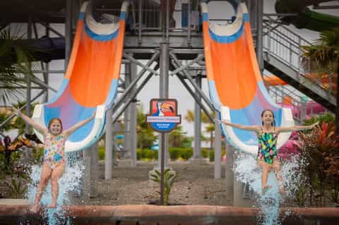 Twin orange water slides with children splashing at the base at a water park